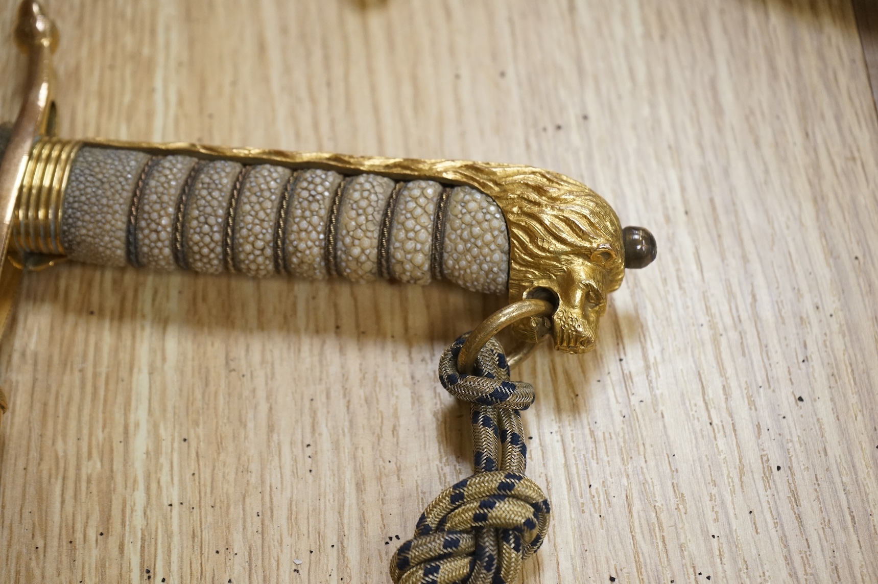 A post 1902 regulation Naval Officer’s dirk with lion’s head pommel, bullion dress knot, shark skin covered grip, in its leather scabbard, the gilt locket engraved with owners initials; CHCO’ R, the blade etched with cro